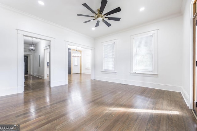 empty room with ceiling fan with notable chandelier, ornamental molding, and dark hardwood / wood-style floors