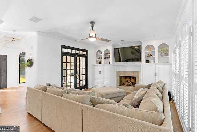 living room featuring ceiling fan, a healthy amount of sunlight, french doors, and built in features