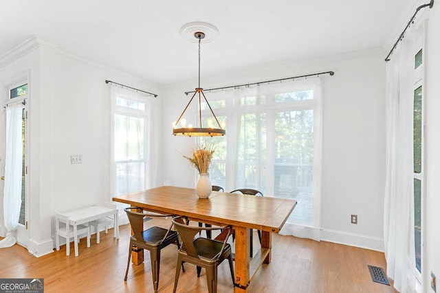 dining area featuring light hardwood / wood-style floors, crown molding, and plenty of natural light