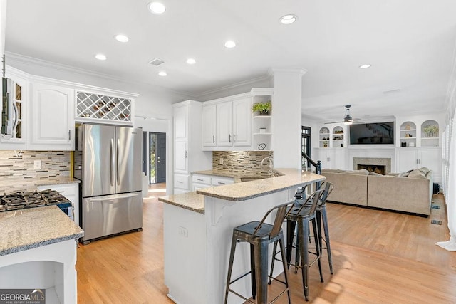 kitchen with white cabinets, a breakfast bar, light stone countertops, and stainless steel refrigerator