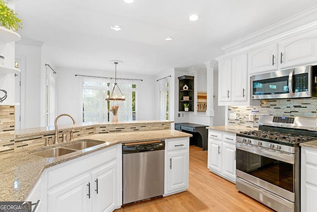 kitchen featuring sink, white cabinetry, light stone counters, hanging light fixtures, and appliances with stainless steel finishes