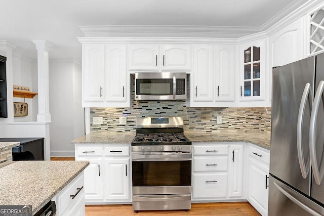 kitchen with white cabinets, stainless steel appliances, light stone counters, and tasteful backsplash