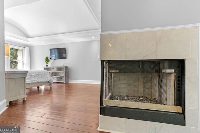 bedroom featuring a fireplace, ornamental molding, and hardwood / wood-style flooring