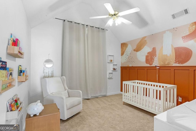 carpeted bedroom with a crib, ceiling fan, and vaulted ceiling