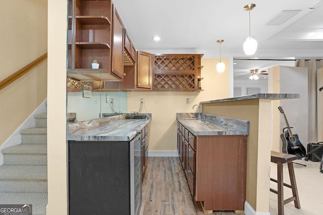 kitchen featuring ceiling fan, pendant lighting, light wood-type flooring, and kitchen peninsula