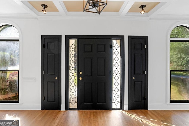 foyer with beamed ceiling, wood-type flooring, ornamental molding, and coffered ceiling