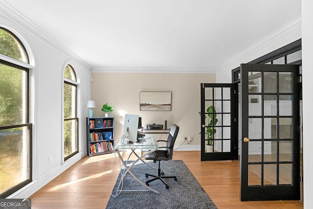 home office with french doors, crown molding, and light hardwood / wood-style floors