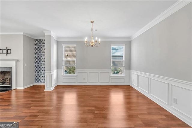 unfurnished dining area with hardwood / wood-style flooring, ornamental molding, and a chandelier