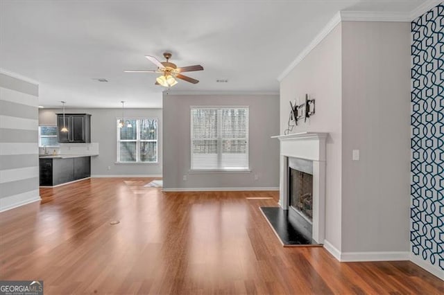 unfurnished living room featuring ceiling fan, crown molding, and dark hardwood / wood-style floors