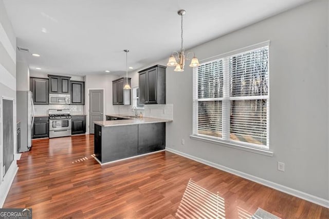 kitchen featuring stainless steel appliances, sink, backsplash, hanging light fixtures, and kitchen peninsula