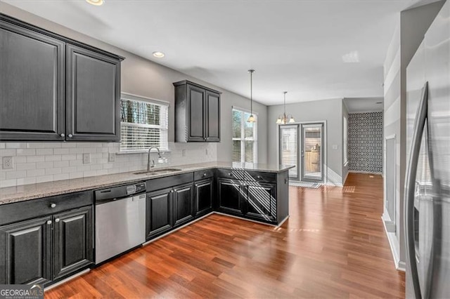 kitchen with wood-type flooring, sink, stainless steel appliances, and pendant lighting