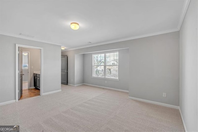 unfurnished bedroom featuring light colored carpet, ornamental molding, and connected bathroom