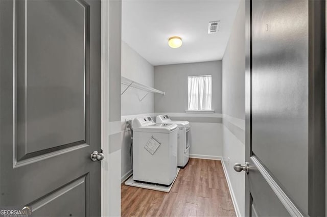 clothes washing area with washer and dryer and light hardwood / wood-style floors