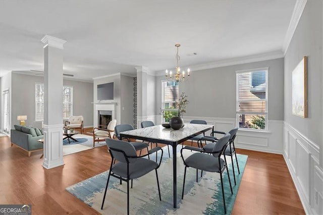 dining space with crown molding, ornate columns, and a notable chandelier