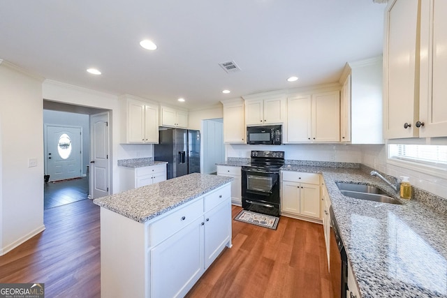 kitchen featuring light stone counters, a center island, black appliances, dark hardwood / wood-style flooring, and sink