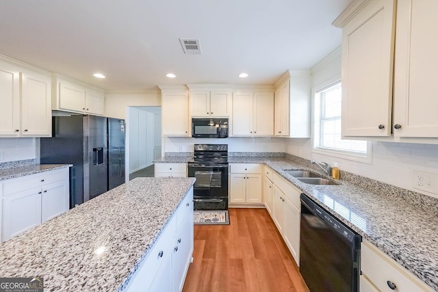 kitchen featuring sink, light wood-type flooring, black appliances, and light stone countertops