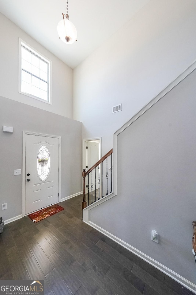 entryway with a towering ceiling and dark hardwood / wood-style flooring