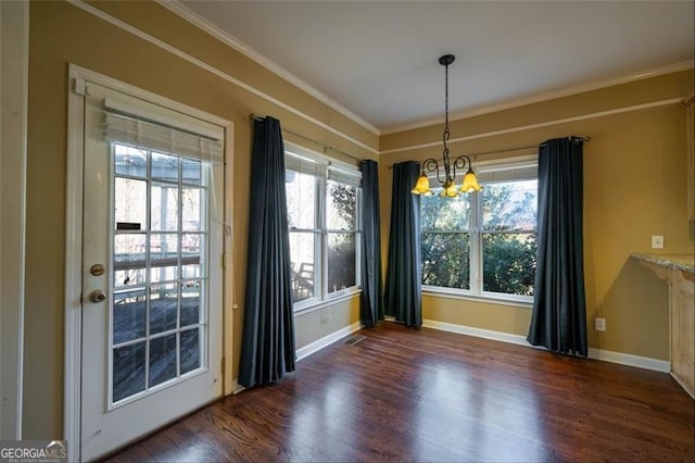 unfurnished dining area with dark hardwood / wood-style flooring, ornamental molding, and a notable chandelier