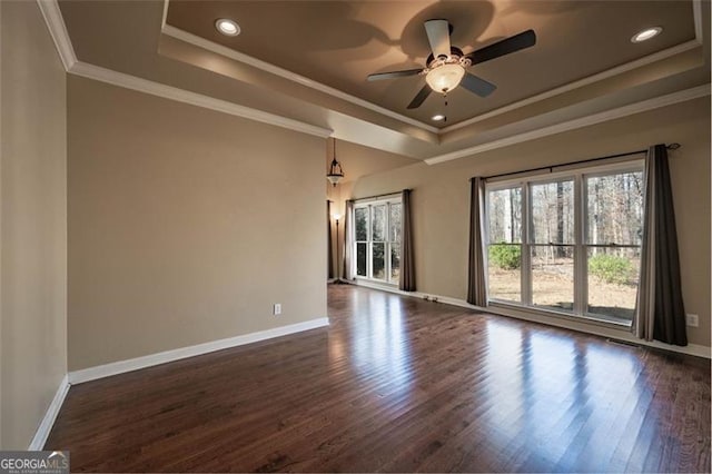 unfurnished room with dark wood-type flooring, a raised ceiling, ceiling fan, and crown molding