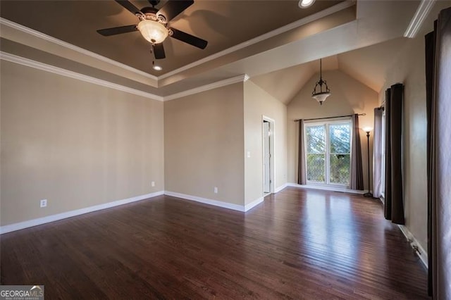 unfurnished room with ceiling fan, a tray ceiling, crown molding, and dark wood-type flooring