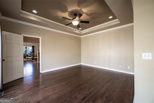 unfurnished room featuring ceiling fan, a tray ceiling, ornamental molding, and dark wood-type flooring