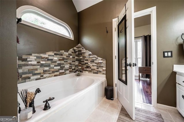 bathroom featuring tile patterned flooring, lofted ceiling, vanity, and a bathing tub