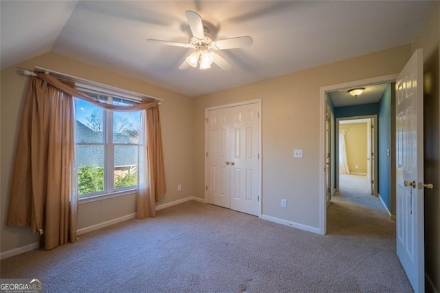 unfurnished bedroom featuring vaulted ceiling, light colored carpet, ceiling fan, and a closet