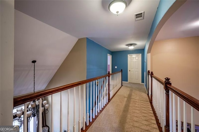 corridor with lofted ceiling and light colored carpet