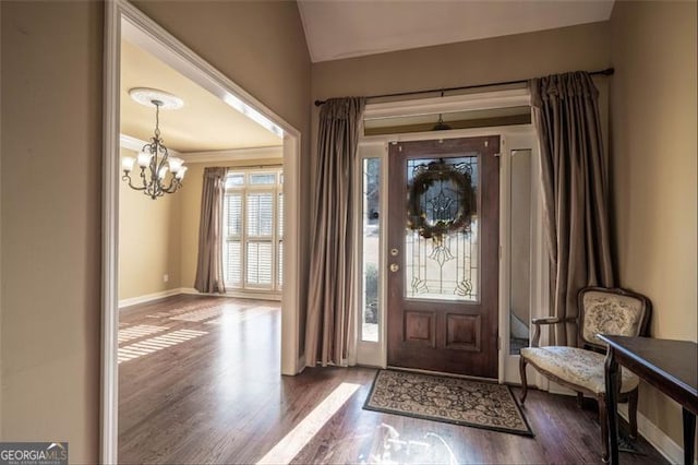 foyer featuring dark wood-type flooring, an inviting chandelier, and lofted ceiling