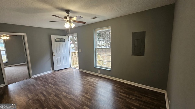 unfurnished room with electric panel, a textured ceiling, ceiling fan, and dark hardwood / wood-style flooring