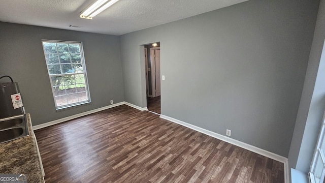 empty room with a textured ceiling and dark hardwood / wood-style flooring