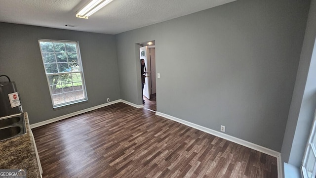 unfurnished room with dark wood-type flooring and a textured ceiling