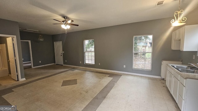 kitchen with sink, white cabinets, ceiling fan, and pendant lighting