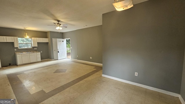 unfurnished living room featuring sink and ceiling fan