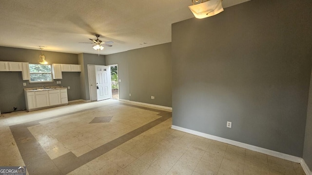 unfurnished living room with ceiling fan and sink