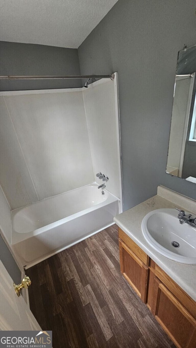 bathroom featuring hardwood / wood-style flooring, a textured ceiling, bathtub / shower combination, and vanity