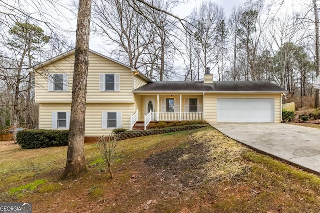 split level home featuring a porch, a front yard, and a garage