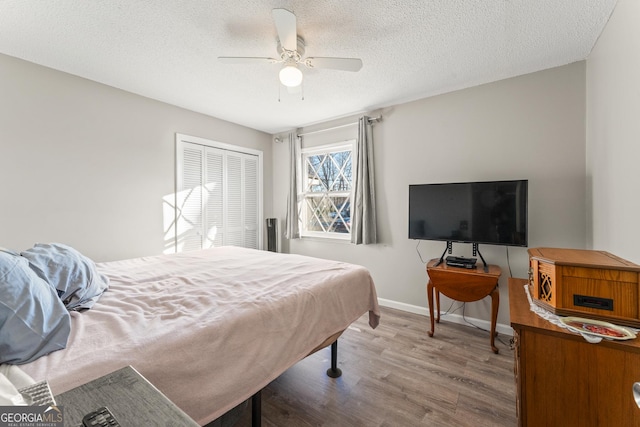 bedroom featuring hardwood / wood-style flooring, a textured ceiling, ceiling fan, and a closet