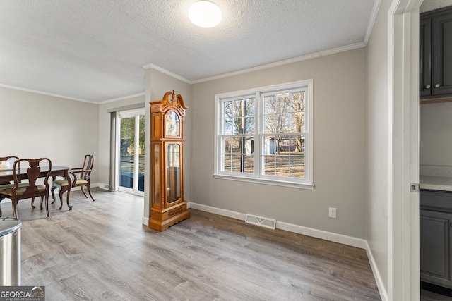 dining room with light wood-type flooring and crown molding