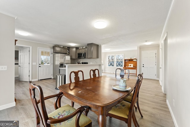 dining area featuring ornamental molding, light wood-type flooring, a textured ceiling, and plenty of natural light