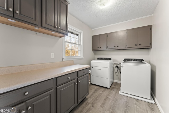 laundry room with washer and dryer, cabinets, a textured ceiling, and light hardwood / wood-style flooring