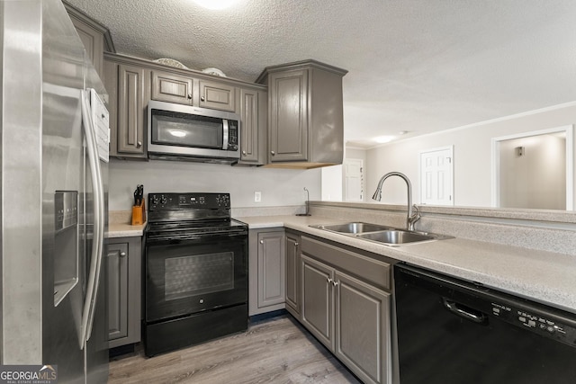 kitchen with a textured ceiling, light hardwood / wood-style floors, black appliances, ornamental molding, and sink