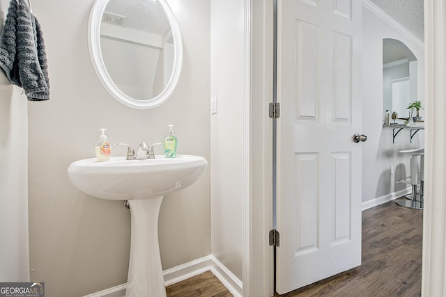 bathroom featuring a textured ceiling, crown molding, and hardwood / wood-style floors