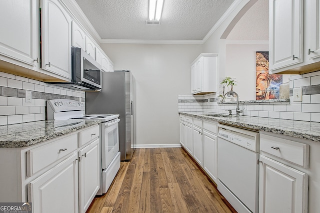 kitchen with white appliances, a textured ceiling, backsplash, white cabinetry, and sink