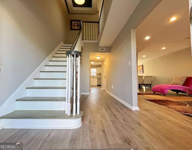 stairway with a towering ceiling and hardwood / wood-style floors