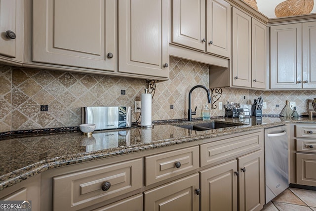 kitchen featuring light tile patterned floors, tasteful backsplash, dark stone countertops, cream cabinetry, and a sink