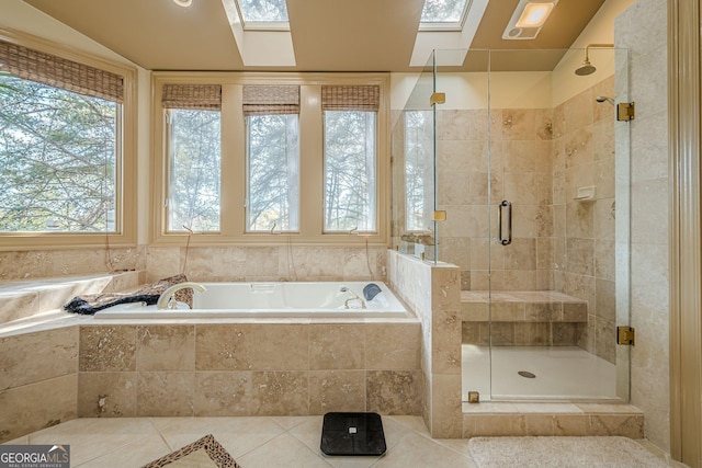 bathroom with tile patterned floors, a skylight, a garden tub, and a shower stall