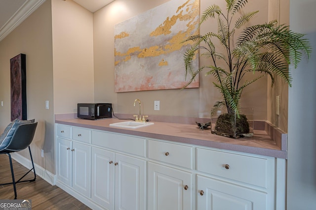 kitchen with white cabinetry, dark wood-style flooring, light countertops, and a sink