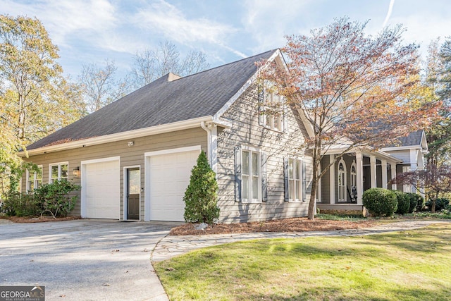 view of side of home featuring a garage, concrete driveway, a yard, and a shingled roof