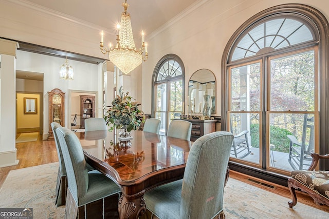 dining space with a notable chandelier, visible vents, ornamental molding, a healthy amount of sunlight, and light wood-type flooring